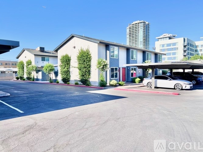 A parking lot with a white car parked in front of a building with the word "AVAILABLE" on it.