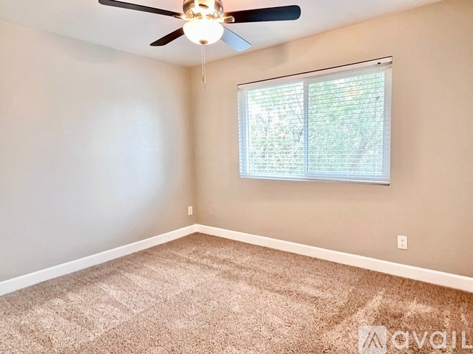 A room with a ceiling fan and a window with blinds.