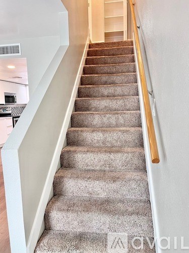 A staircase with a beige carpet and wooden handrail.