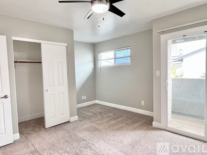 A room with a ceiling fan and a door leading to another room.
