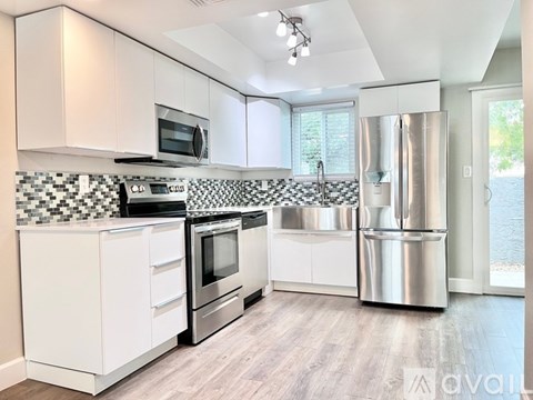 A kitchen with white cabinets and a black and white checkered backsplash.