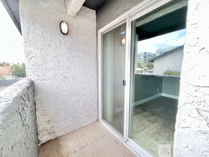 A balcony with a glass door and a white wall.