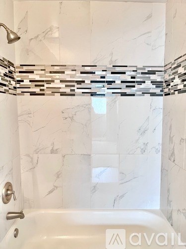 A bathroom with a marble tile shower and a white bathtub.