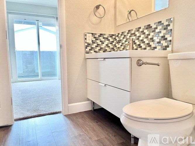 A white toilet with a white tank and a white cabinet with a white drawer is in a bathroom with a mirror and a tiled wall.
