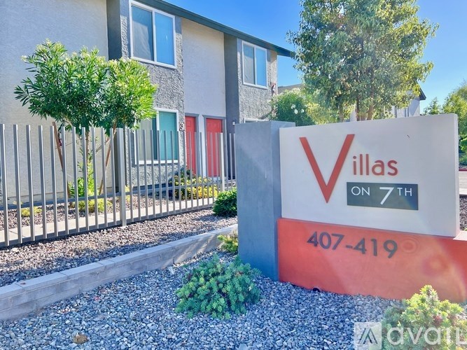 A sign for Villas on 7th with a phone number in front of a building.