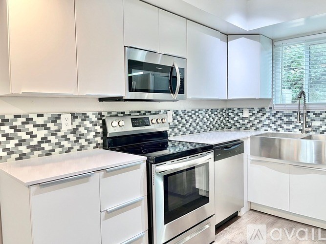 A kitchen with white cabinets and black and white tiled backsplash.