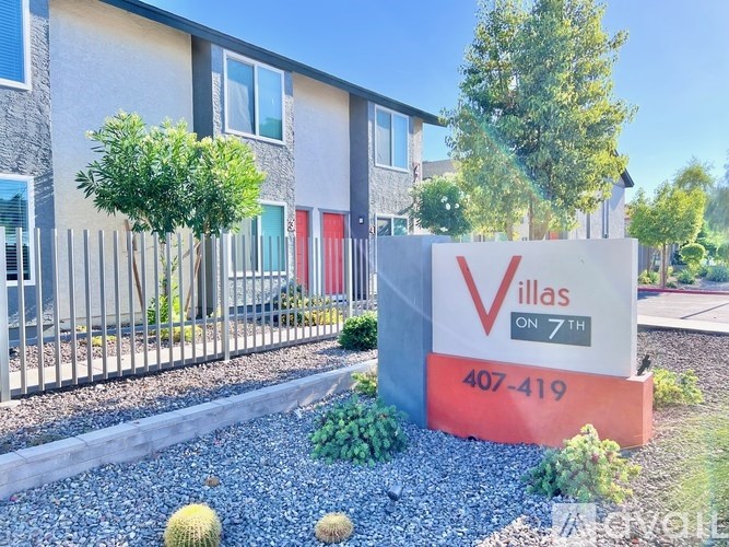 A sign for Villas on 7th with a phone number in front of some houses.