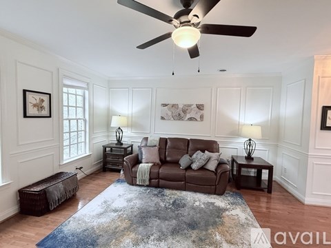 A living room with a brown couch and a blue rug.
