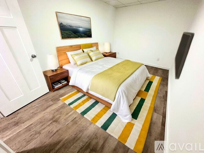 A bedroom with a bed, nightstand, and a painting on the wall.