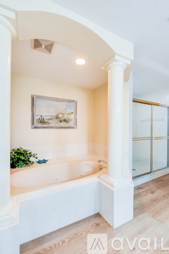 A bathroom with a large tub and a painting on the wall.