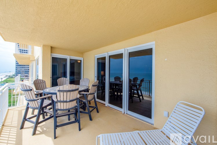A patio with a table and chairs overlooking the ocean.
