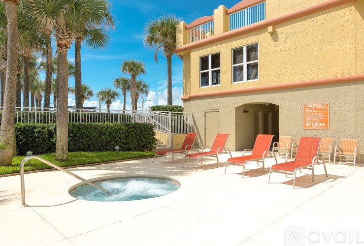 A pool with a hot tub and chairs in front of a building.