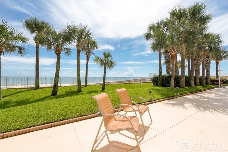 Two chairs are on a patio overlooking the ocean.