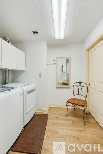 A laundry room with a washer and dryer, a brown rug, and a chair.