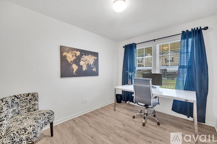A room with a world map on the wall, a desk with a laptop, and a chair.
