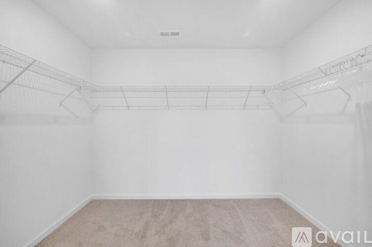 A sparsely furnished room with a carpeted floor and a wall-mounted shelf.