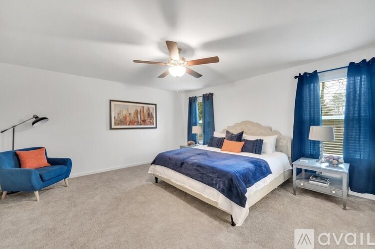 A bedroom with a bed, chair, and ceiling fan.