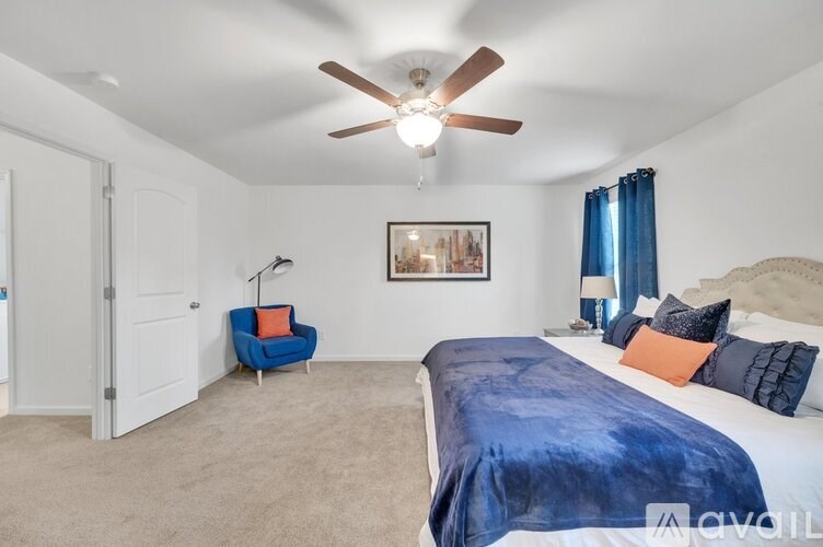 A bedroom with a blue bedspread and a ceiling fan.