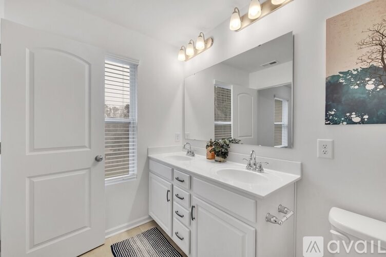 A white bathroom with a sink, mirror, and a painting on the wall.