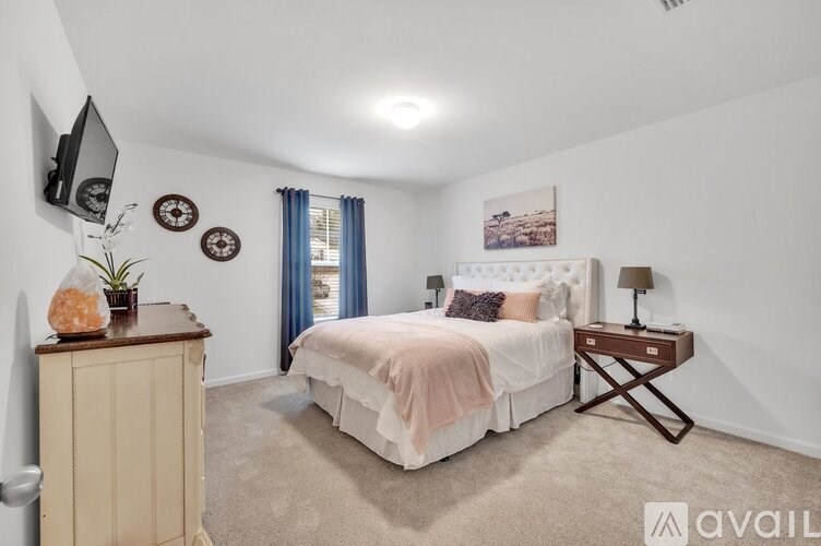 A bedroom with a bed, nightstand, and a television on the wall.