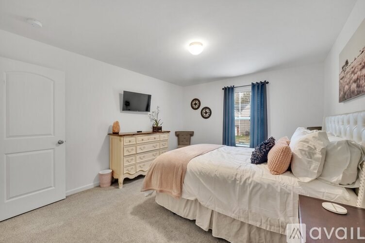 A bedroom with a bed, dresser, and window.