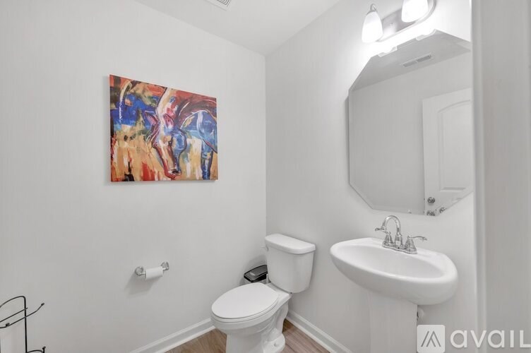 A bathroom with a toilet, sink, and a painting on the wall.