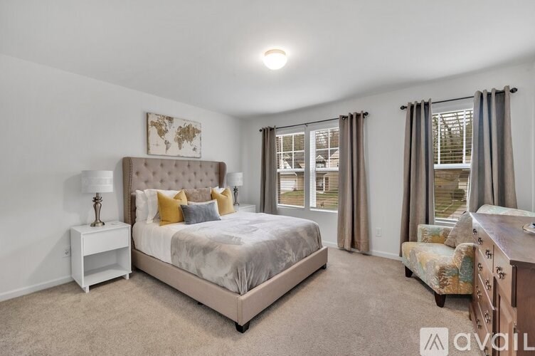 A bedroom with a large bed, a nightstand, a chair, and a window with curtains.