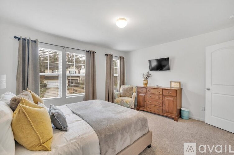 A bedroom with a bed, a dresser, and a window with curtains.