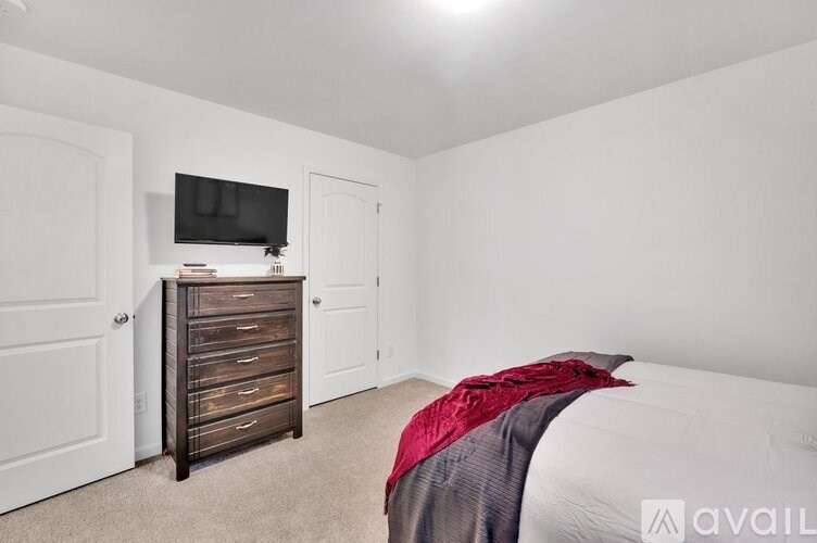 A bedroom with a bed, dresser, and a television on the wall.