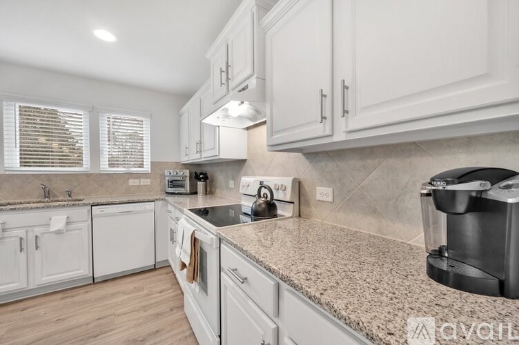 A kitchen with white cabinets and a granite countertop.