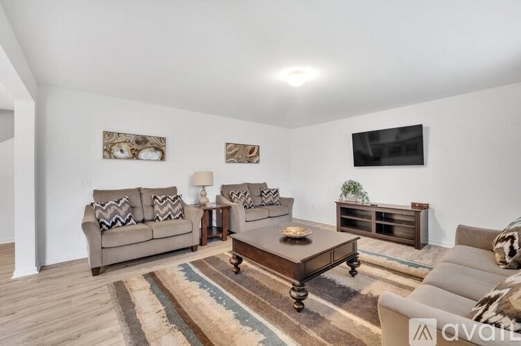 A living room with a couch, coffee table, and a flat screen TV mounted on the wall.