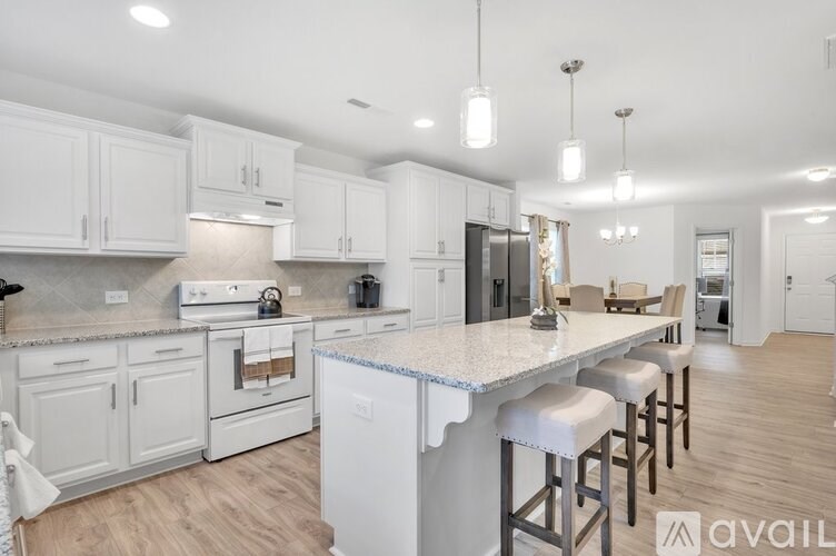 A kitchen with white cabinets and a large island with bar stools.