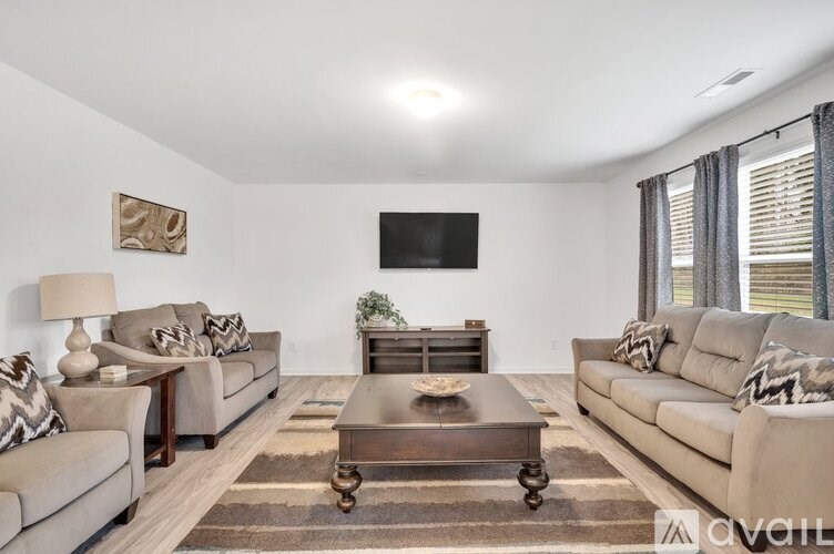 A living room with a large couch, a coffee table, and a flat-screen TV mounted on the wall.