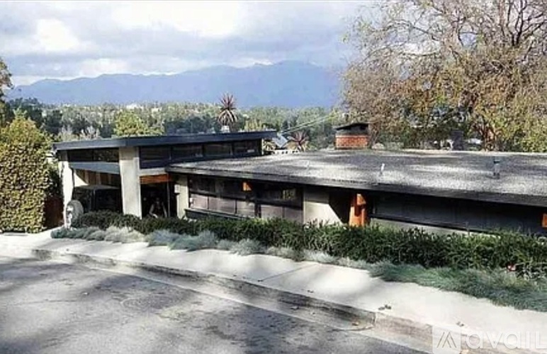 A modern building with a flat roof and a parking lot in front.