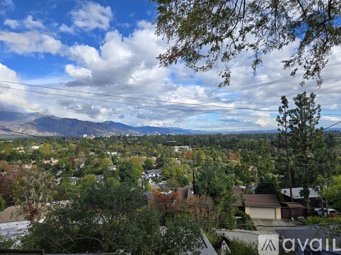A suburban landscape with houses and trees under a cloudy sky.