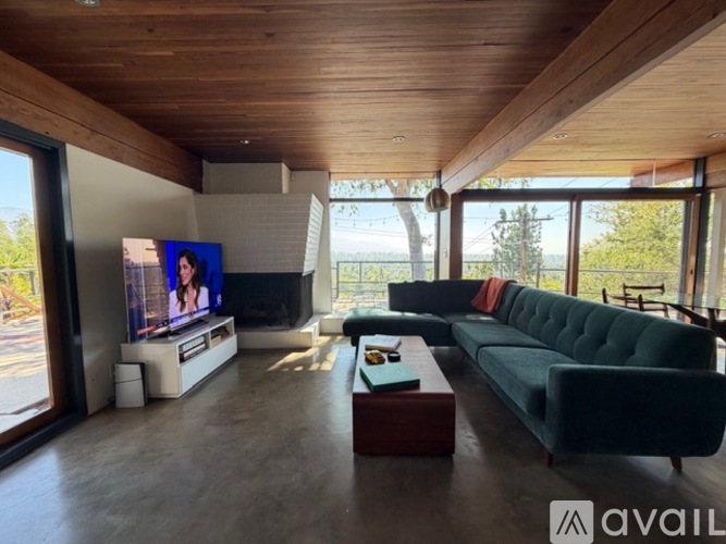 A living room with a black leather couch and a wooden table.