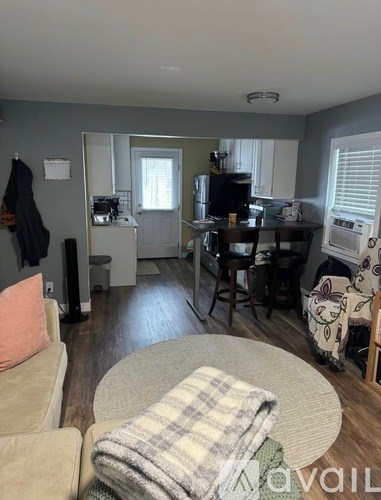 A living room with a couch, a chair, and a table with a blanket on it.