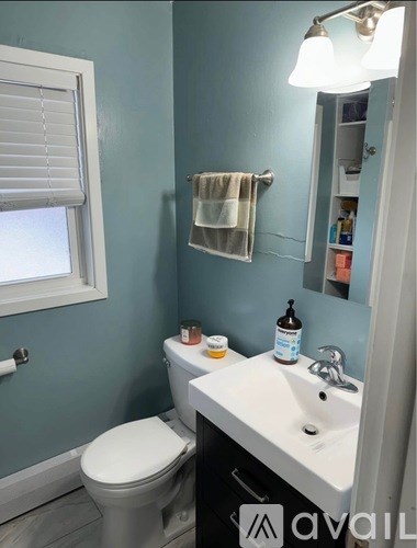 A bathroom with a toilet, sink, and mirror.