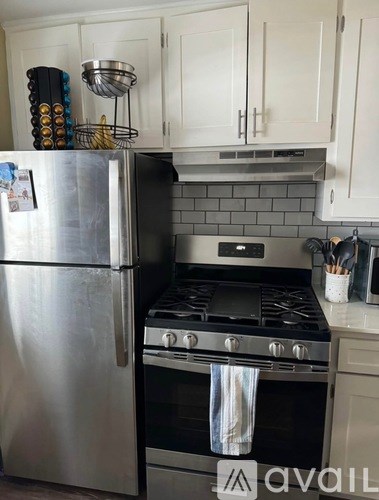 A kitchen with a stainless steel refrigerator and a black stove top.