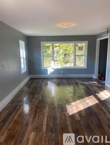 A room with wooden flooring and a window letting in natural light.