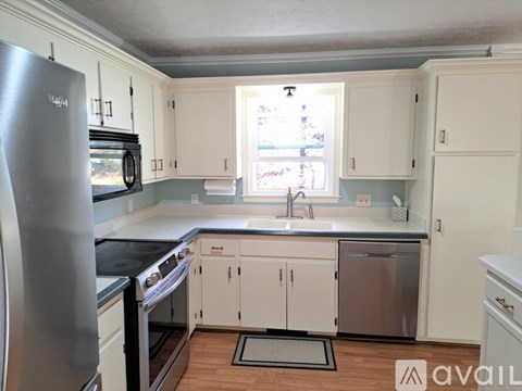 A kitchen with white cabinets and a stainless steel refrigerator.