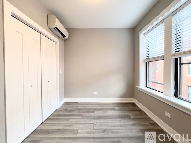 A room with a window, a door, and a wall-mounted air conditioner.