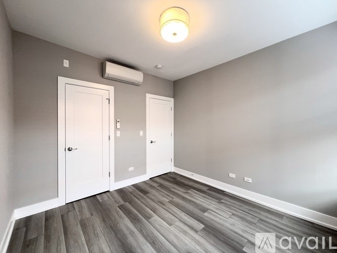 A room with a wooden floor and two white doors.