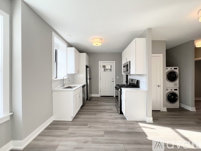 A kitchen with white cabinets and a grey floor.