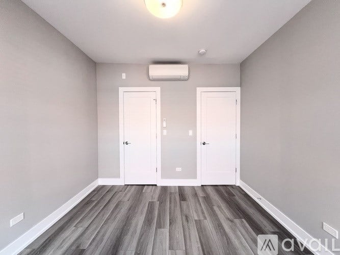 A room with two white doors and a wooden floor.