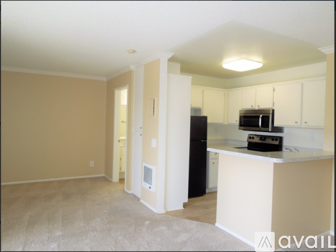A kitchen area with a black refrigerator and white countertops.