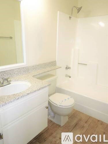 A white toilet with a blue design on the lid is in a bathroom with a white tub and sink.