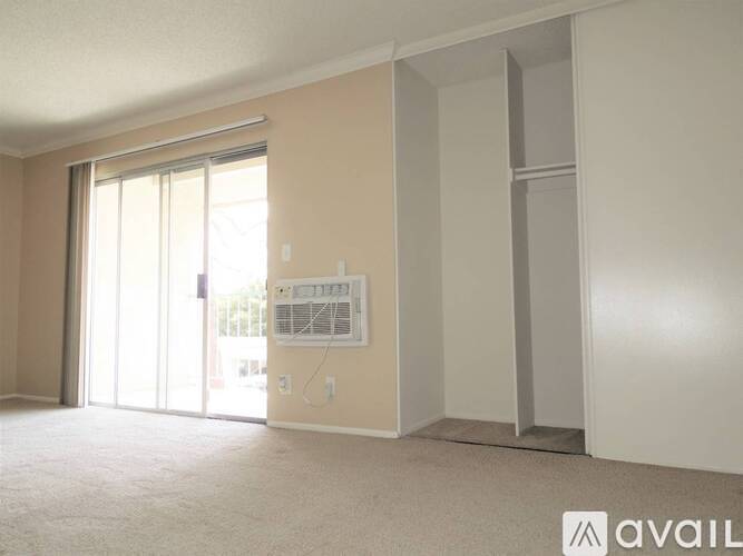 A room with a sliding glass door and a white wall with a window.