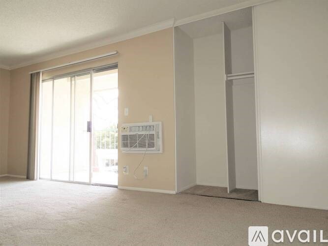 A room with a sliding glass door and a white wall with a window.