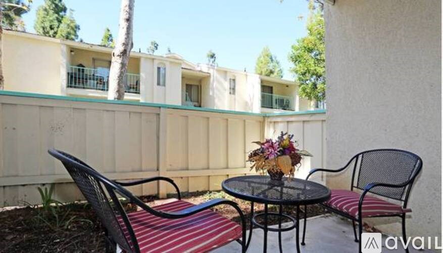 A patio with a table, two chairs, and a vase of flowers.